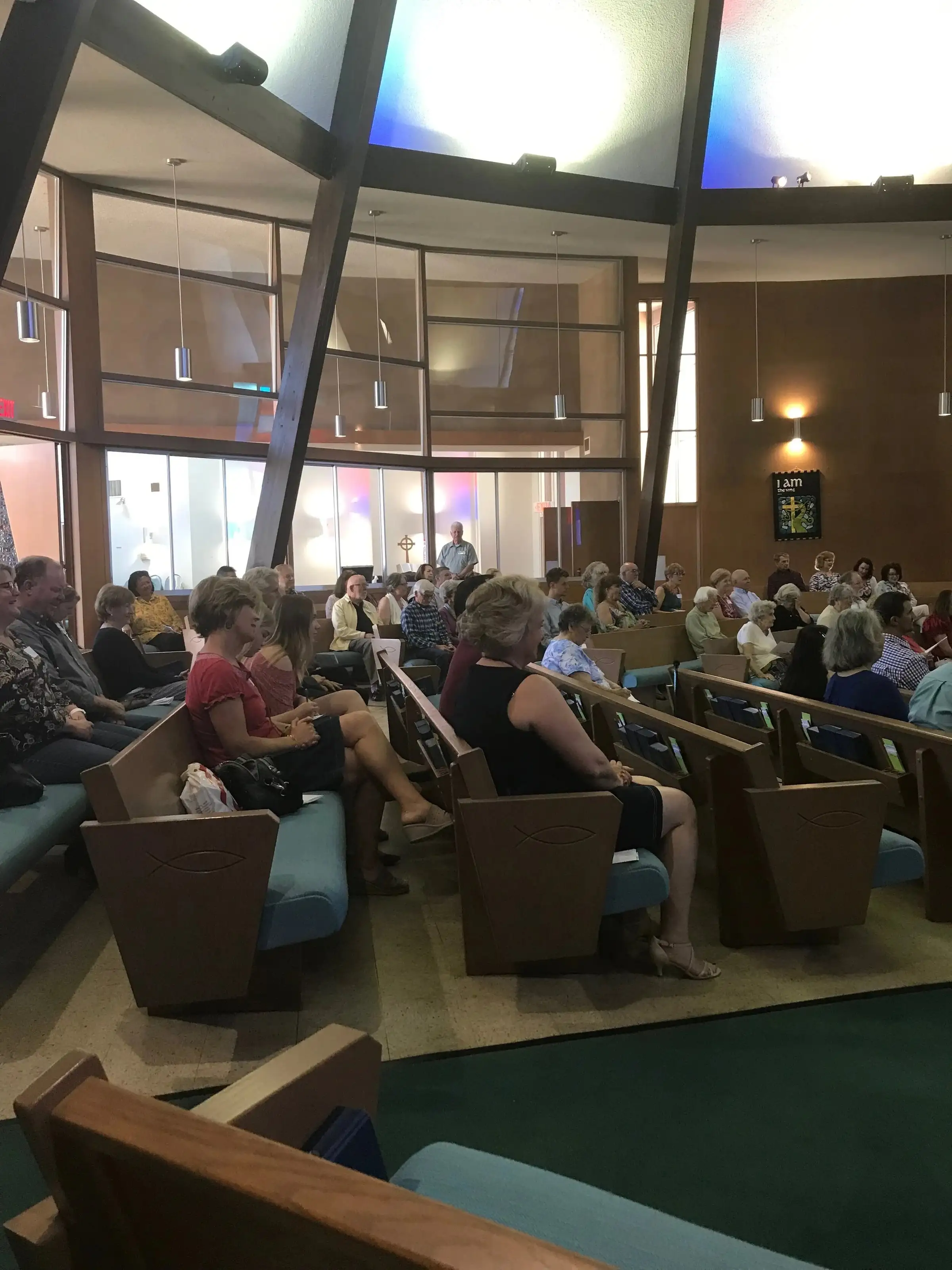 The congregation seated in the sanctuary beneath its tall stained-glass windows